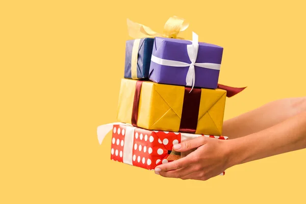 Partial view of girl holding gift boxes isolated on yellow — Stock Photo