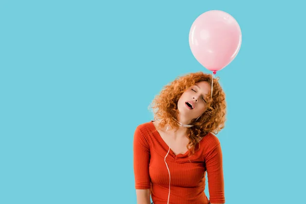 Erschöpfte rothaarige Frau mit rosa Luftballon auf blauem Grund — Stockfoto