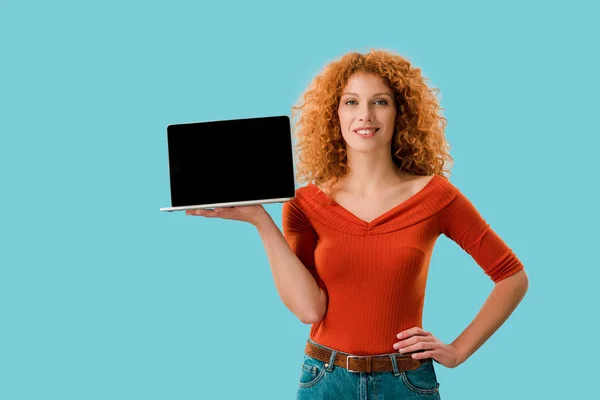 Chica rizada sosteniendo portátil con pantalla en blanco aislado en azul - foto de stock