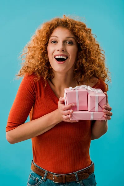 Beautiful excited girl holding gifts isolated on blue — Stock Photo