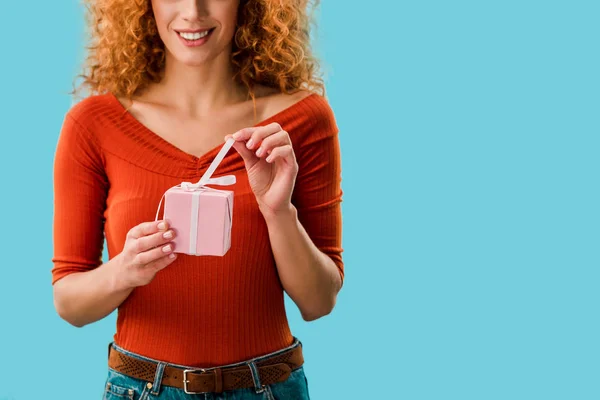 Vista recortada de la mujer sonriente sosteniendo caja de regalo aislado en azul - foto de stock