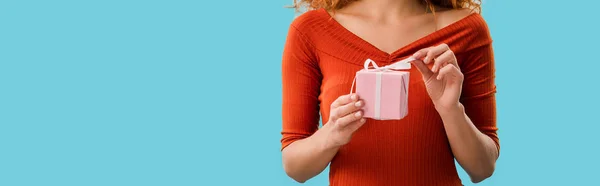 Vista recortada de la mujer joven sosteniendo caja de regalo aislado en azul - foto de stock