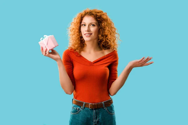 Femme bouclée souriante avec boîte cadeau isolé sur bleu — Photo de stock