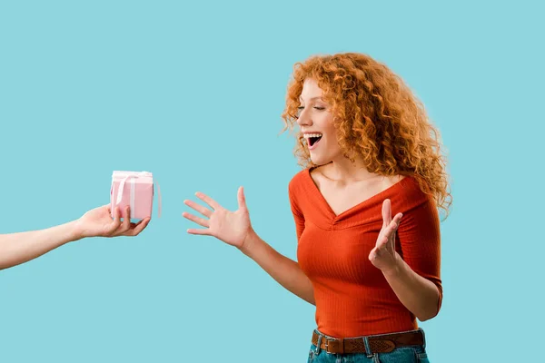 Excited redhead girl with gift box isolated on blue — Stock Photo