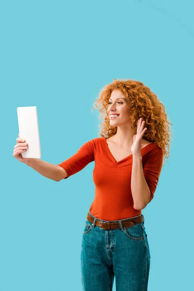 Mulher sorrindo acenando e tendo chamada de vídeo em tablet digital isolado em azul — Fotografia de Stock
