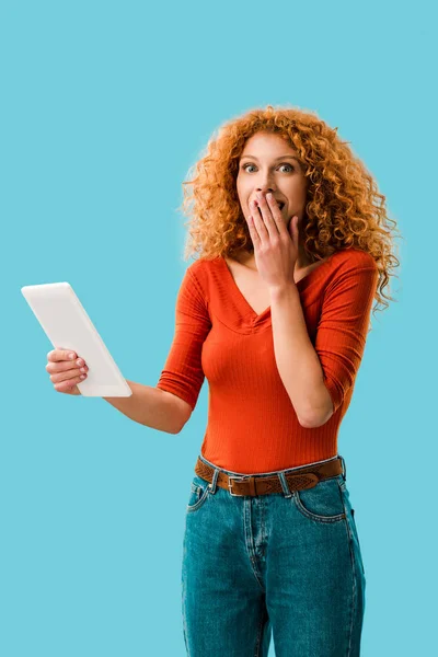 Mujer impactada atractiva usando tableta digital aislada en azul - foto de stock