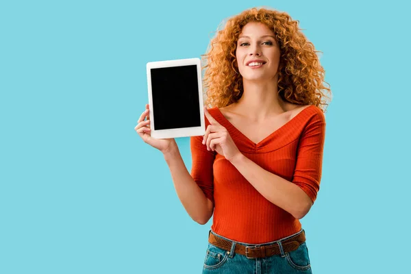 Приваблива усміхнена жінка, що показує цифровий планшет з порожнім екраном ізольовано на синьому — стокове фото