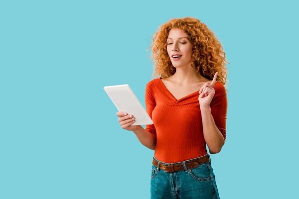 Beautiful curly woman pointing up and using digital tablet isolated on blue — Stock Photo