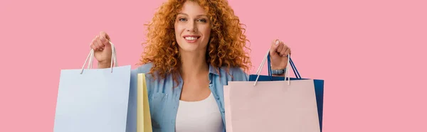 Улыбающаяся женщина, держащая сумки с покупками, на розовом — стоковое фото