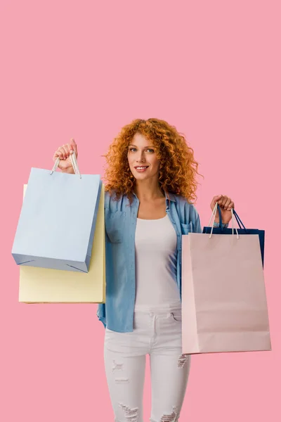 Sorridente menina segurando sacos de compras, isolado em rosa — Fotografia de Stock