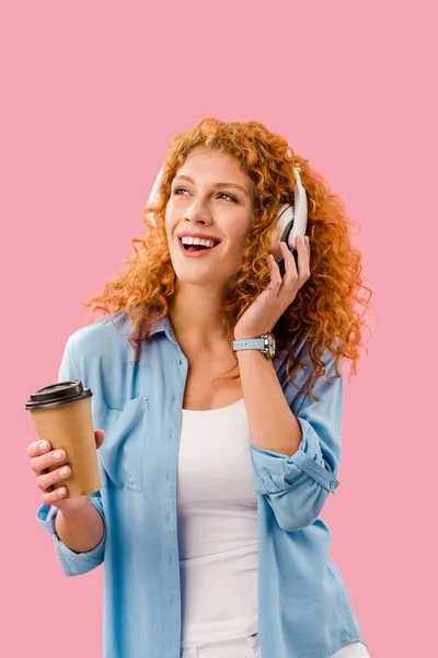 Hermosa chica alegre escuchando música con auriculares en la pausa de café, aislado en rosa - foto de stock