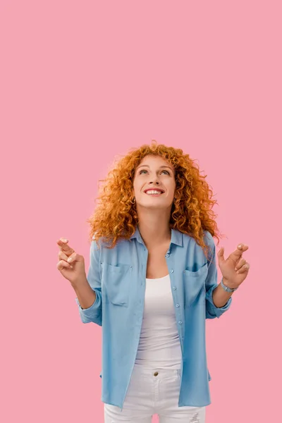 Atractiva chica alegre cruzando sus dedos aislados en rosa - foto de stock