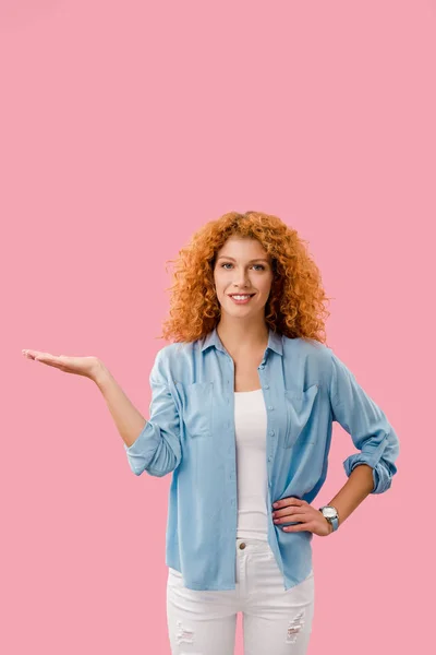 Attractive redhead woman presenting something isolated on pink — Stock Photo