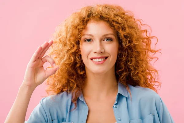 Sonrisa atractiva pelirroja chica mostrando ok signo aislado en rosa - foto de stock