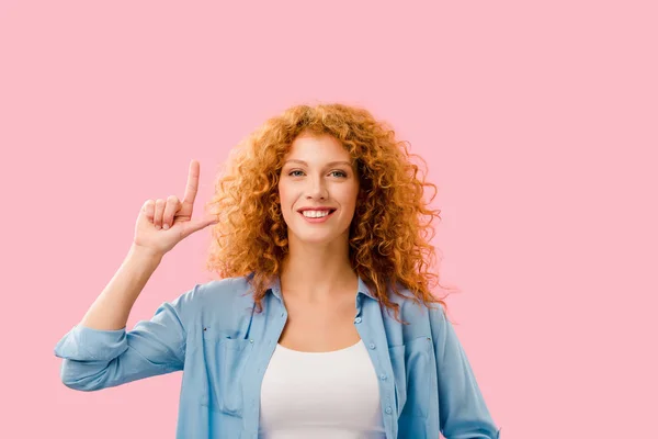 Cheerful redhead girl pointing up and having idea isolated on pink — Stock Photo