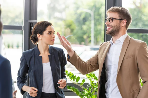 Zwei Kollegen in offizieller Kleidung stehen in der Nähe von Fenstern im Büro — Stockfoto