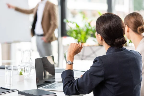 Vista para trás de duas mulheres de negócios sentadas à mesa durante a apresentação no cargo — Fotografia de Stock
