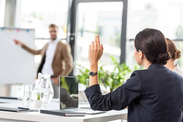 Назад взгляд предпринимательницы, поднимающей руку во время конференции в офисе — стоковое фото