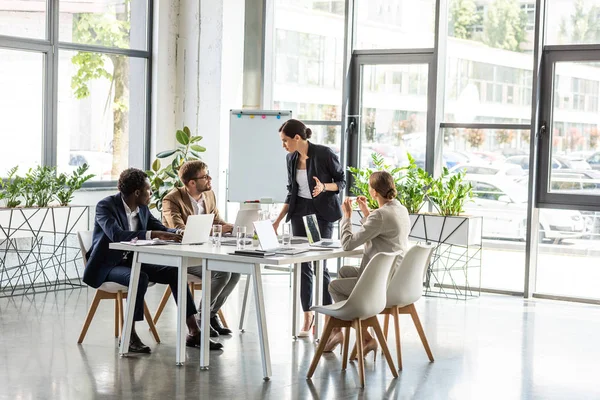 Multiethnic businesspeople at table with laptops during conference in office — Stock Photo