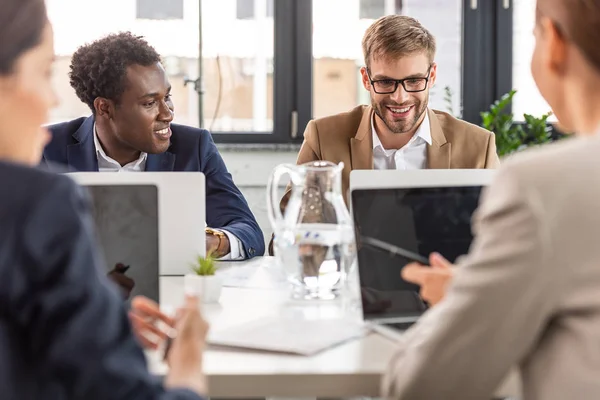 Focus selettivo di imprenditori multietnici seduti ai tavoli durante la conferenza in carica — Foto stock