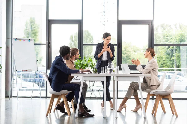 Empresários multiétnicos sentados à mesa durante conferência no escritório — Fotografia de Stock