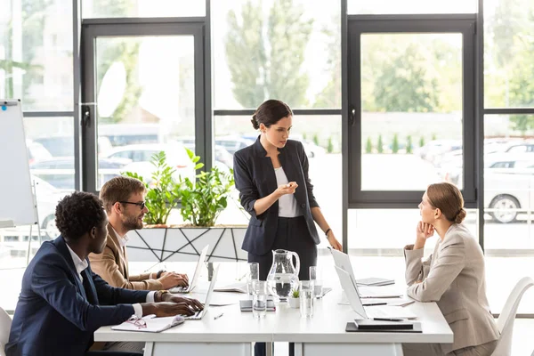 Multiethnische Geschäftsleute sitzen bei Konferenz im Büro an Tischen — Stockfoto