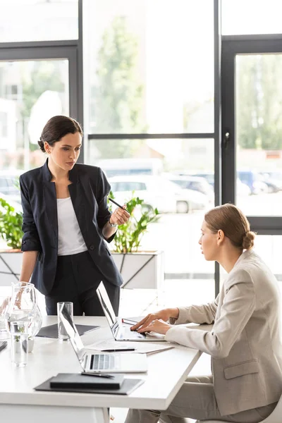 Zwei Geschäftsfrauen in formeller Kleidung, die einander anschauen und sich im Büro unterhalten — Stockfoto
