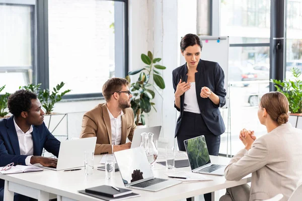 Empresários multiétnicos sentados à mesa durante conferência no escritório — Fotografia de Stock