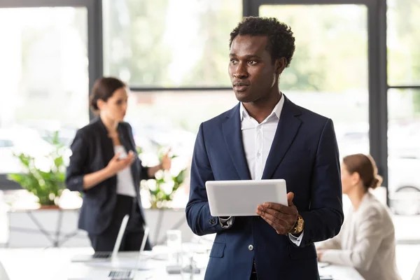 Homme d'affaires afro-américain en tenue formelle tenant tablette numérique au bureau — Photo de stock