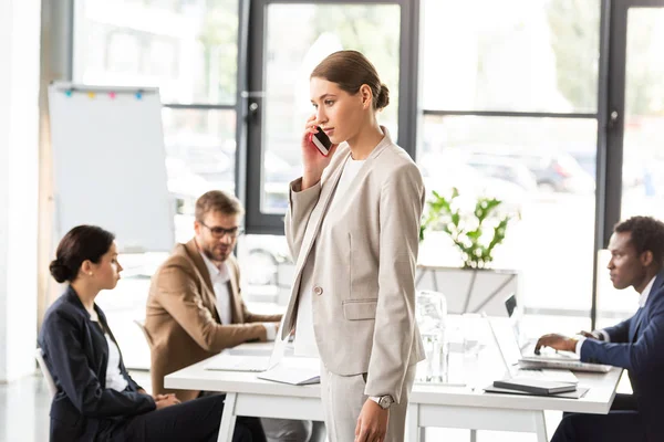 Geschäftsfrau in offizieller Kleidung spricht im Büro auf Smartphone — Stockfoto