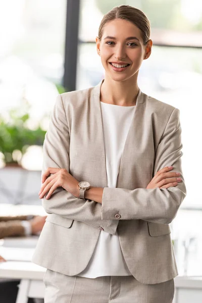 Вид на уверенную деловую женщину в формальной одежде, стоящую со скрещенными руками в офисе — стоковое фото