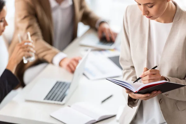 Vue partielle de l'écriture femme d'affaires dans le manuel dans le bureau — Photo de stock