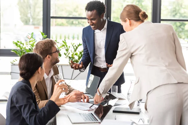 Smiling multiethnic businesspeople at table during conference in office — Stock Photo