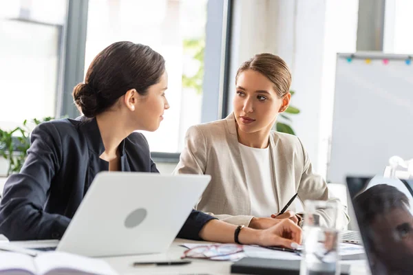 Duas mulheres de negócios no desgaste formal na mesa olhando uma para a outra durante a conferência no escritório — Fotografia de Stock