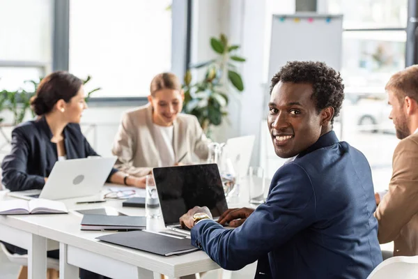 Des hommes d'affaires multiethniques en tenue de cérémonie à table pendant la conférence au bureau — Photo de stock