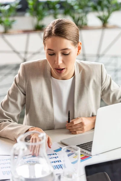 Fokussierte Geschäftsfrau schaut sich Dokumente an, während sie im Büro am Tisch sitzt — Stockfoto