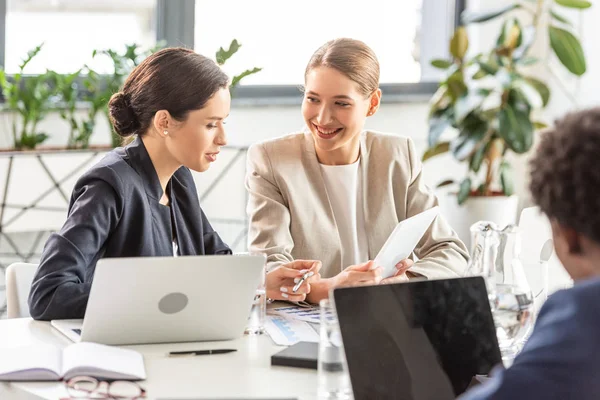 Vista parziale di imprenditori multietnici a tavola con computer portatili in ufficio — Foto stock