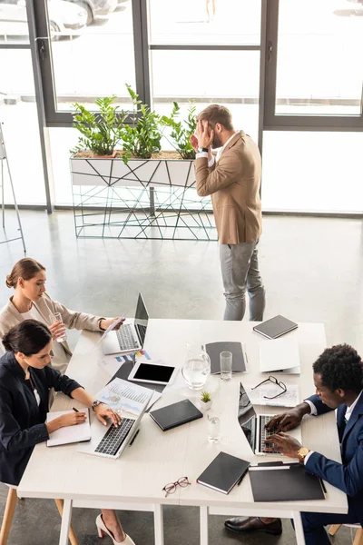 Overhead view of multiethnic businesspeople in formal wear at table during conference in office — Stock Photo