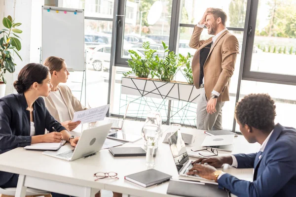 Multiethnic businesspeople in formal wear at table during conference in office — Stock Photo