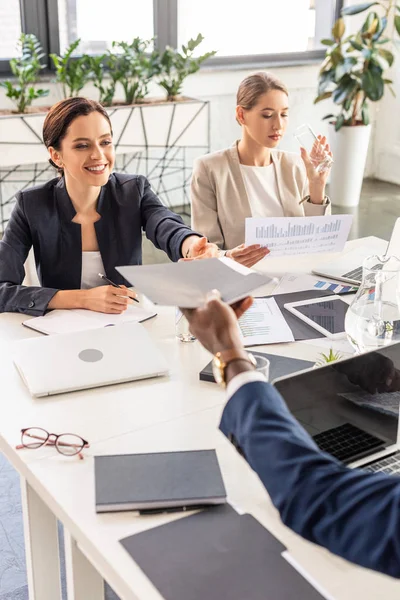 Visão parcial de empresários multiétnicos em desgaste formal à mesa durante conferência no escritório — Fotografia de Stock