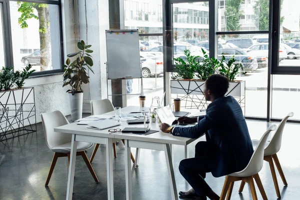 Hombre de negocios afroamericano sentado en la mesa y usando el ordenador portátil - foto de stock