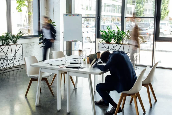 Vue arrière de l'homme d'affaires afro-américain dormant sur la table au bureau — Photo de stock