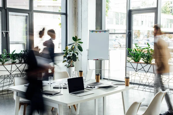 Silhouettes of three multiethnic colleagues working and walking in office — Stock Photo