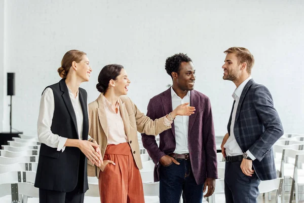 Four multiethnic colleagues in formal wear talking in conference hall — Stock Photo