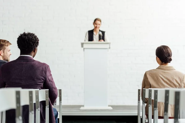 Selective focus of multiethnic businesspeople sitting during conference in conference hall — Stock Photo