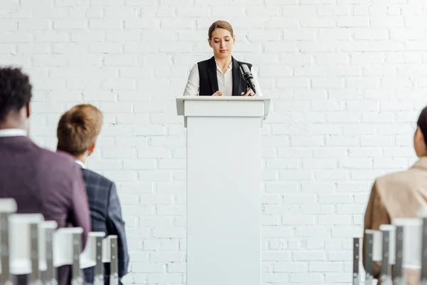 Attraktive Geschäftsfrau, die während der Konferenz im Konferenzsaal steht und spricht — Stockfoto