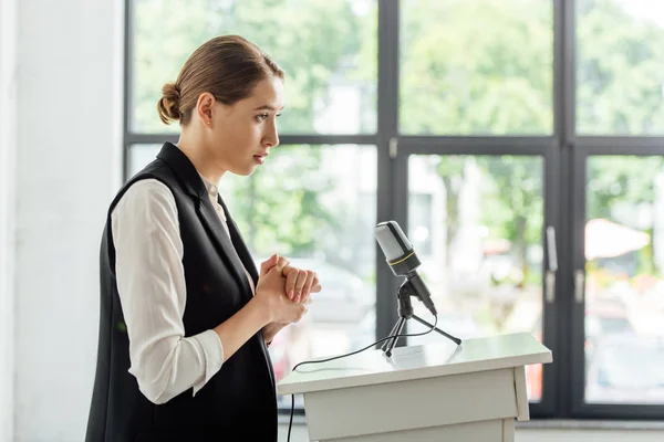 Side view of attractive businesswoman standing during conference in conference hall — Stock Photo