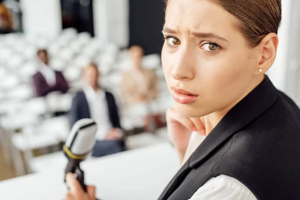 Selektiver Fokus der attraktiven Geschäftsfrau, die während der Konferenz in die Kamera blickt — Stockfoto