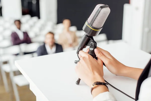 Vista ritagliata della donna d'affari che tiene il microfono durante la conferenza nella sala conferenze — Foto stock