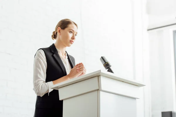 Attractive businesswoman standing and looking away during conference in conference hall — Stock Photo